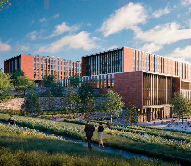 A rendering of the new CISA HQ building and central utility plant. The buildings are red brick and surrounded by green landscaping. There is a large, terraced office building in the center with two main towers. Two tall smokestacks from the utility plan are just visible on the right side.